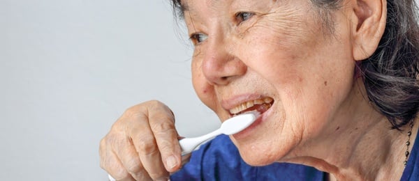 Elderly woman brushing her teeth