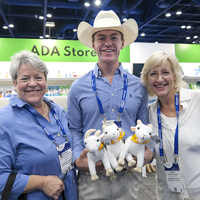 Smiling SmileCon attendees with stuffed animals goats in Dental Central